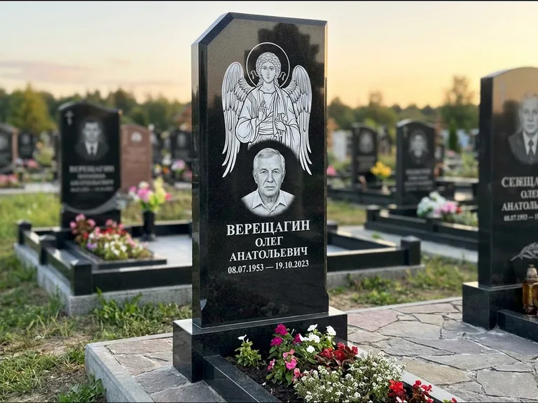 Памятник с гравировкой иконы: стела с резным навершием и нимбом в золоте — гравировка образа Спасителя, высокие разросшиеся туи полукругом, работа «Мельникова» в Самаре