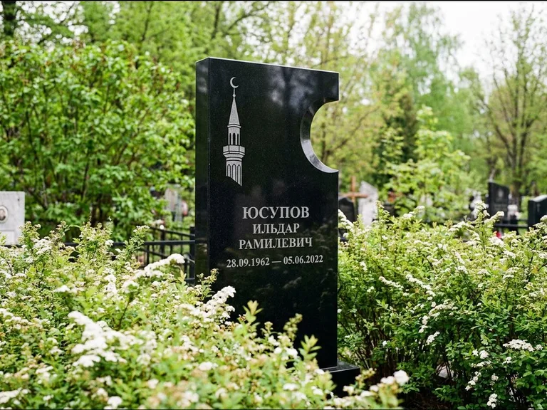 Мусульманский памятник с гравировкой мечети: стела с боковым вырезом в форме полумесяца — гравировка минарета с полумесяцем, низкие кусты спиреи в цвету, работа «Юсупов» в Самаре